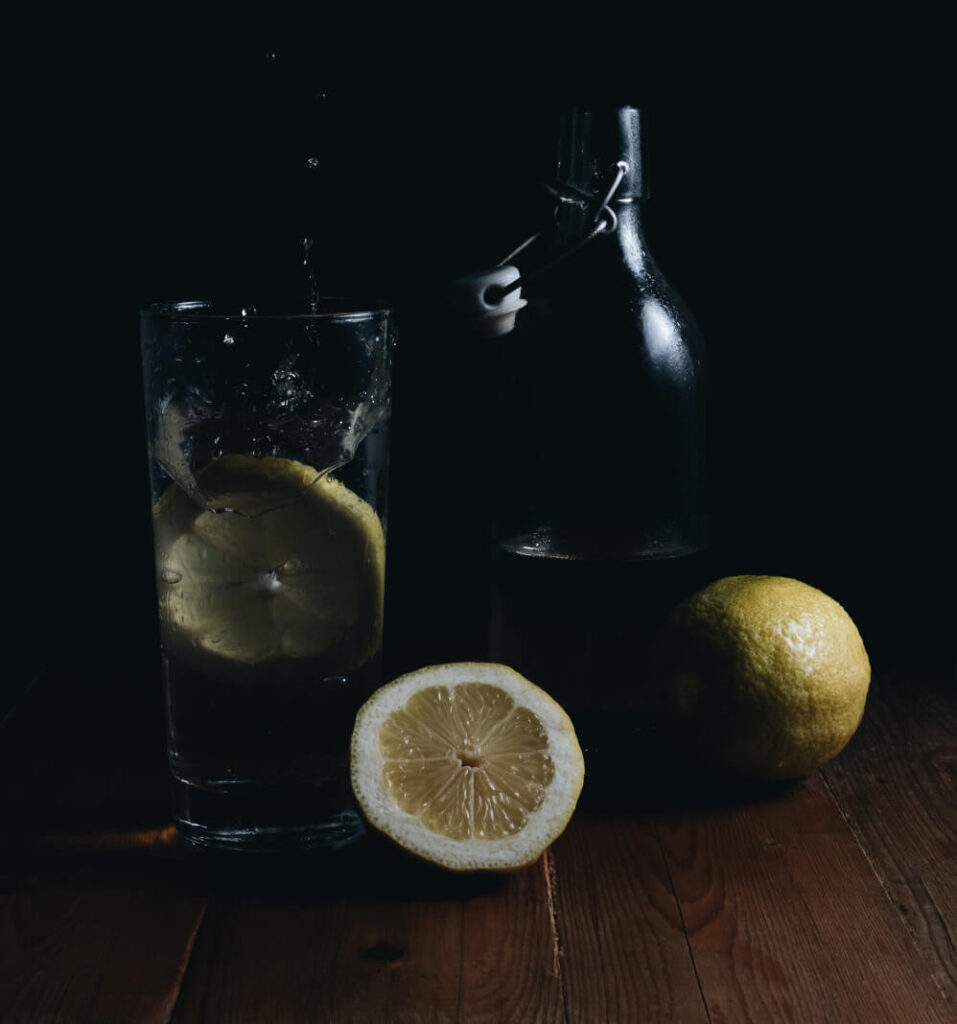 Infused Water vor einem schwarzen Hintergrund mit einer Zitrone